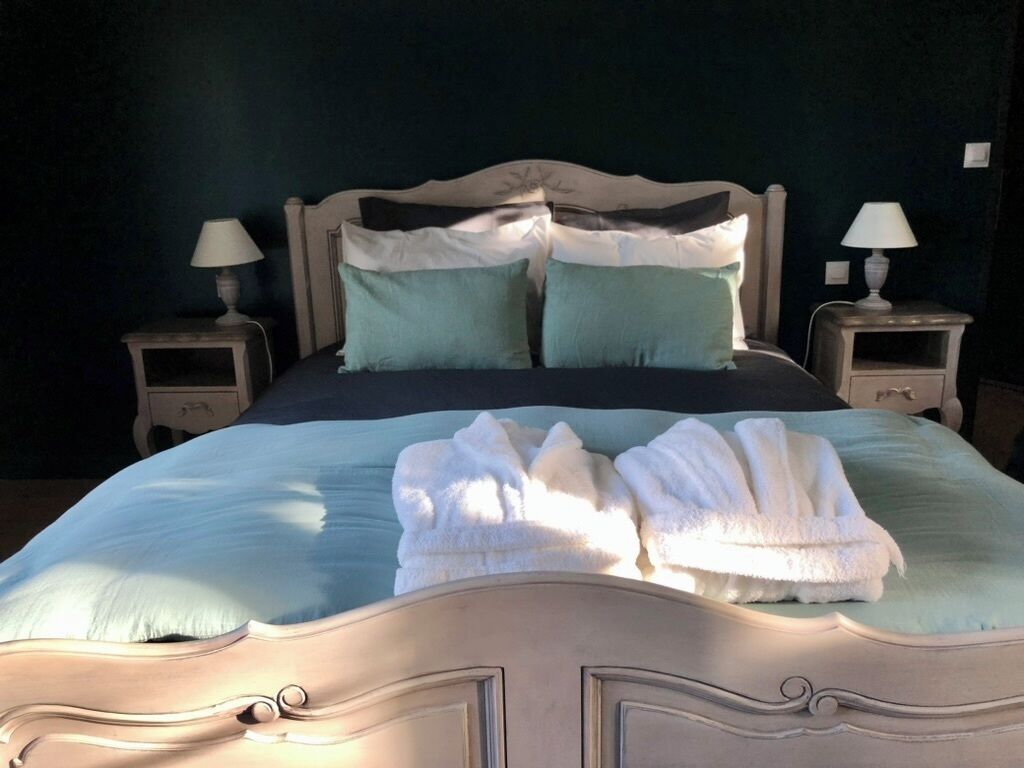A bed with a headboard, two bedside tables with lamps, and a set of towels on the bed.