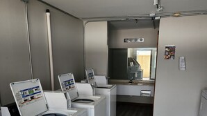 Une buanderie avec quatre machines à laver blanches, un grand miroir et un plancher en bois.