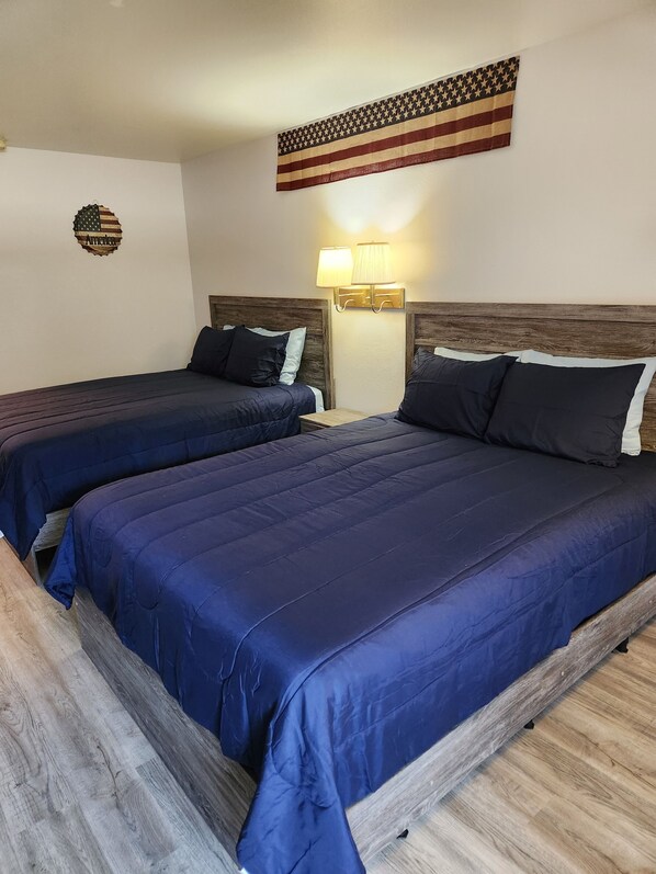 Une chambre d’hôtel avec deux lits, des têtes de lit en bois et un drapeau américain accroché au mur.
