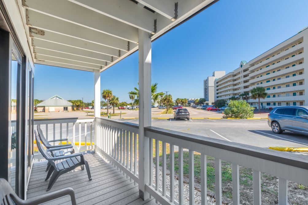 A hotel balcony with a view of a parking lot and a multi-story building.