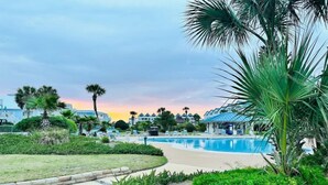 Ein Resort mit Schwimmbad, Palmen und Blick auf den Sonnenuntergang.