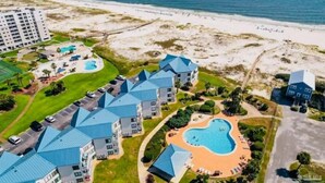 Ein Resort mit mehreren Gebäuden, einem großen Schwimmbecken und Blick auf den Strand.