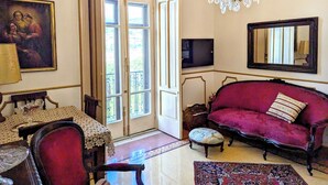 A living room with a red sofa, a chandelier, a television, and a painting on the wall. - B&B Salerno Royal Suite Central Station (Salerno)