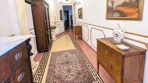 A hallway with a marble-topped dresser, a wooden cabinet, a patterned rug, and a decorative vase on a side table. - B&B Salerno Royal Suite Central Station (Salerno)