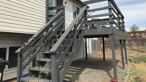 Un edificio residencial con terraza de madera y escalera que lleva a un espacio cubierto.