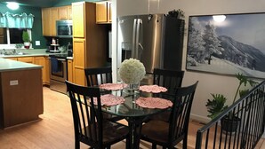 Una cocina moderna con armarios de madera, electrodomésticos de acero inoxidable y un comedor con mesa y sillas de vidrio.