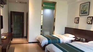 Een hotelkamer met twee bedden, een bureau en een groen bord aan de muur.