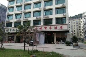 A multi-story building with a sign indicating a business center. - Zhicheng Business Hotel (Jianghua)