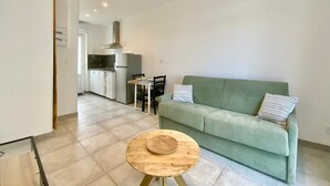 Un salon moderne avec un canapé vert, une table basse en bois et un coin repas comprenant une table et des chaises.