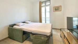 Une chambre à coucher de taille réduite, comprenant un lit, un petit bureau et un téléviseur.