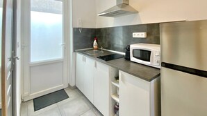 Une cuisine compacte avec des meubles blancs, une hotte en acier inoxydable, un four à micro-ondes et une cuisinière.