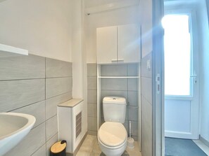 A modern bathroom with a toilet, a sink, and a shower area. - Le Sully, City Center Studio with A/C (Nîmes)