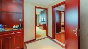 A hallway with a wooden door and a kitchen area visible through an open door. - Boss Hotel (Huangshan City)