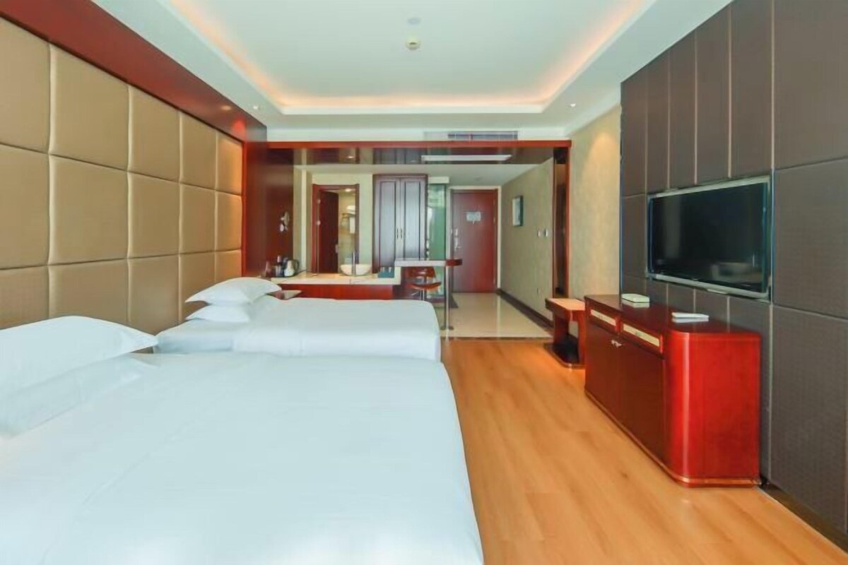 Una habitación de hotel con una cama grande, televisión, escritorio y espejo.