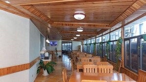 A spacious indoor area with wooden ceiling beams, large windows, and multiple seating tables. - Boss Hotel (Huangshan City)