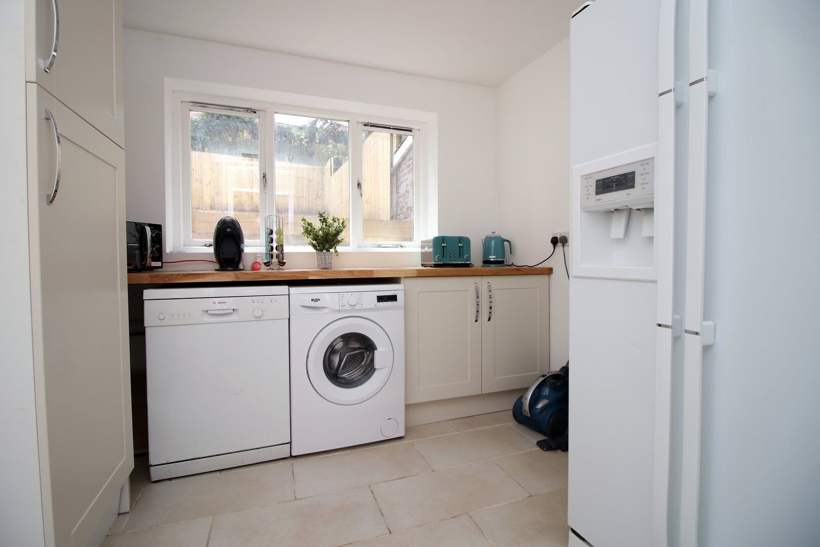 A compact kitchen with a washing machine, a toaster, and a kettle on the counter.