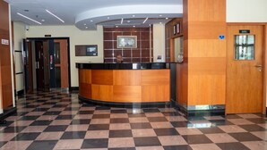 Un'area reception con pavimento a scacchi, una scrivania e una porta con la scritta 'OFFICE'.