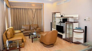Un soggiorno moderno con un divano in pelle, un tavolino da caffè in vetro e una TV a schermo piatto su un mobile in legno.