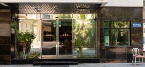 A modern building with a glass entrance, a sign reading "4020 Road", and a chair outside. - ONE PAVALION (Manama)