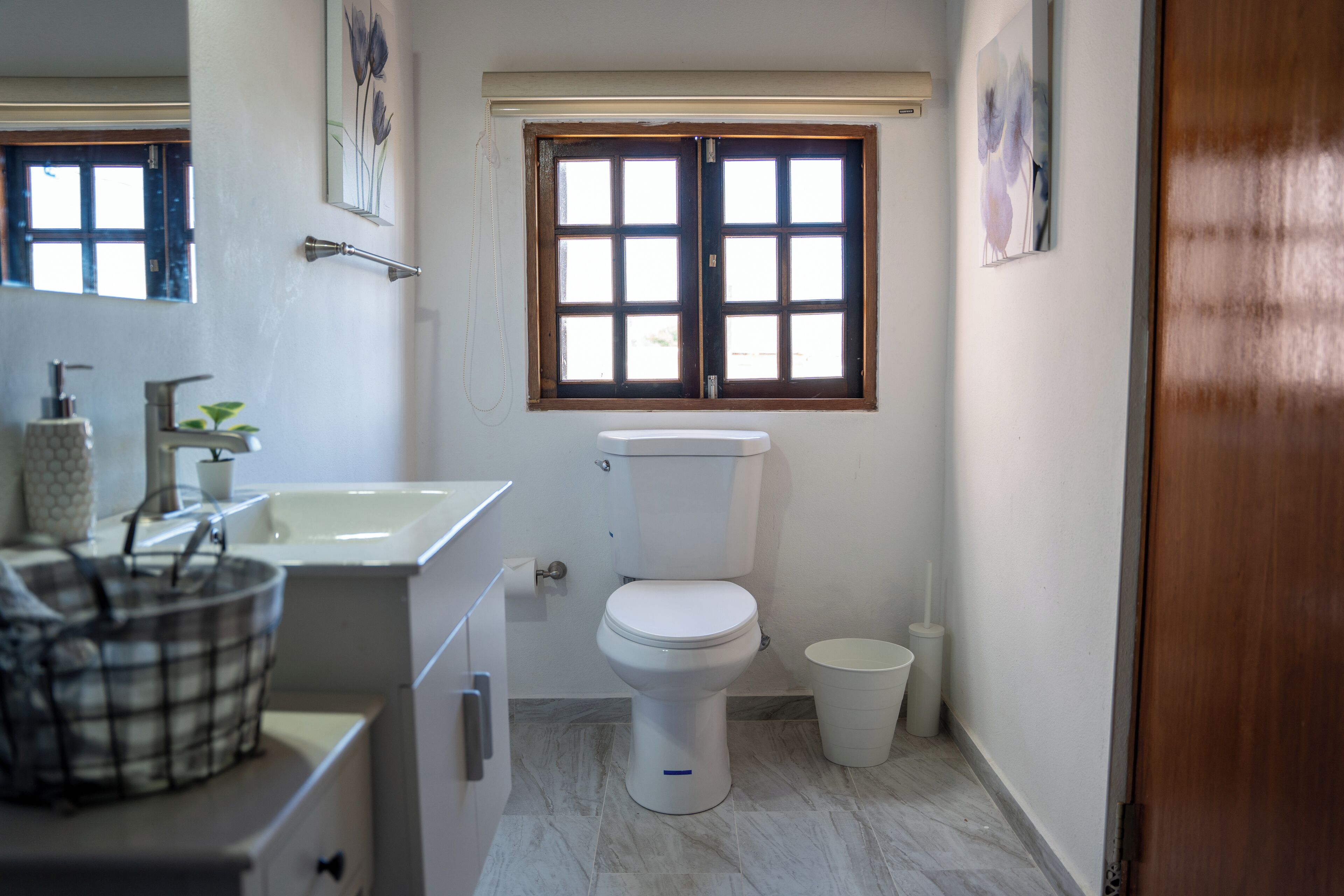 Un baño pequeño y limpio con inodoro, lavamanos y ventana.