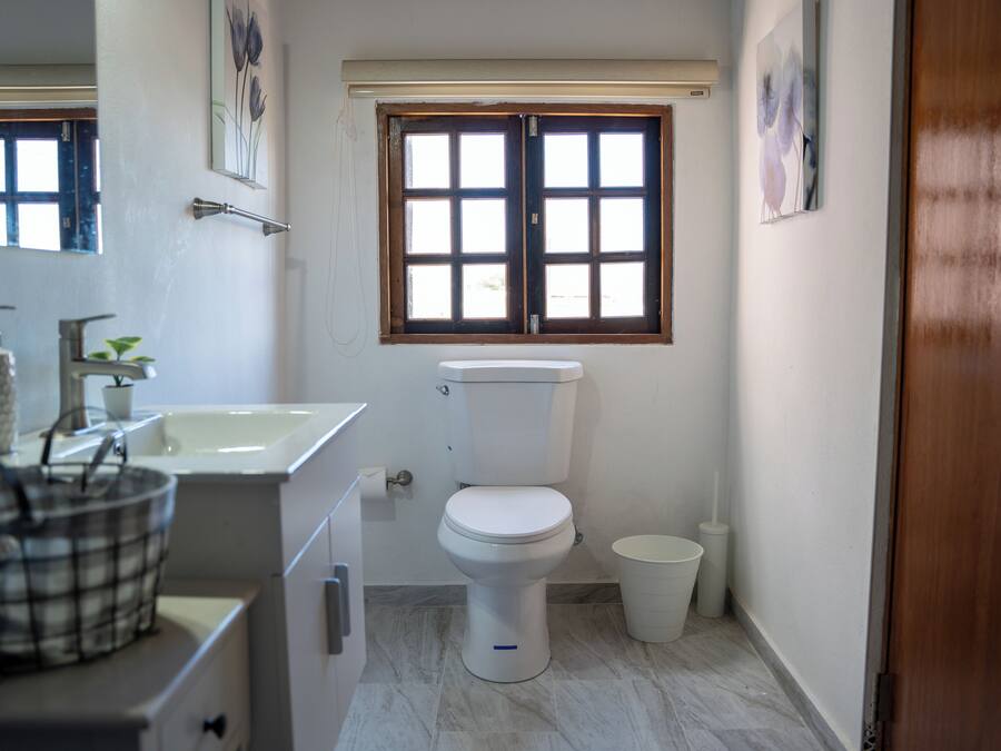 Une petite salle de bain propre, équipée de toilettes, d’un lavabo et d’une fenêtre.