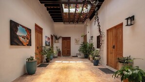 A hallway with a tiled floor, wooden doors, and potted plants. - Hugo's Rental (San Juan)