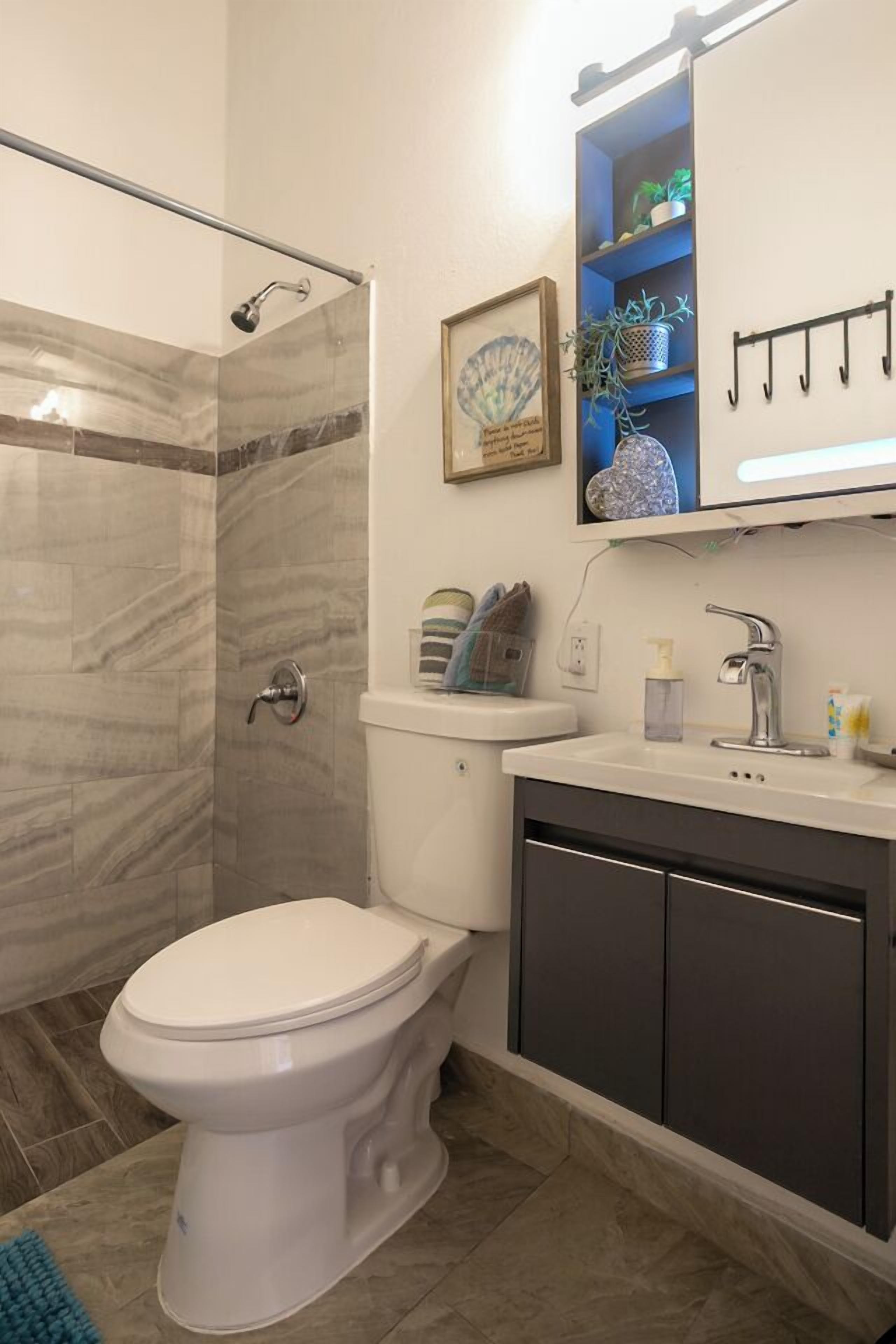 A bathroom with a shower, toilet, sink, and cabinet.