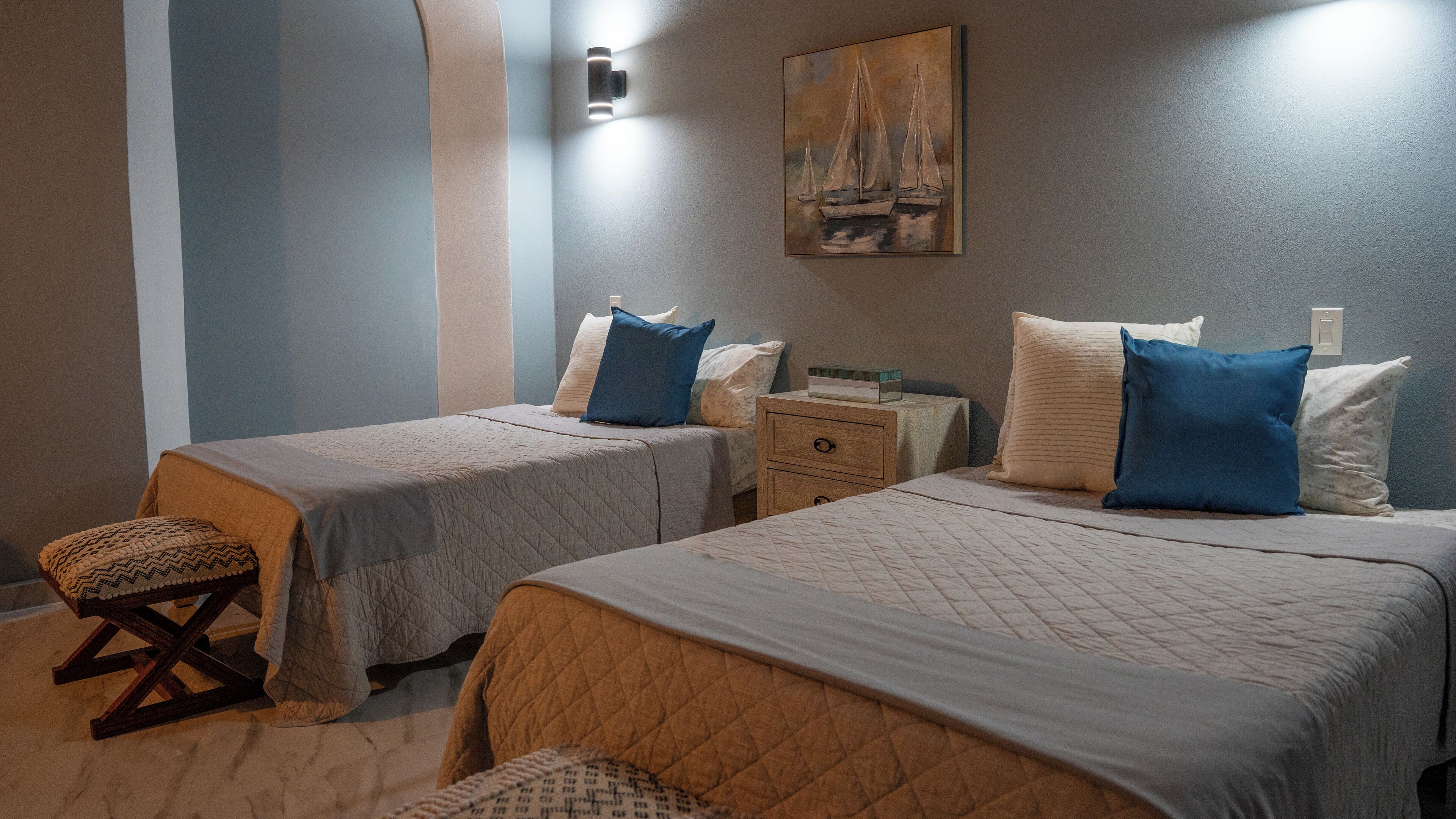Ein Hotelzimmer mit zwei Betten, einem Nachttisch, einem kleinen Tisch und einer Wandleuchte.