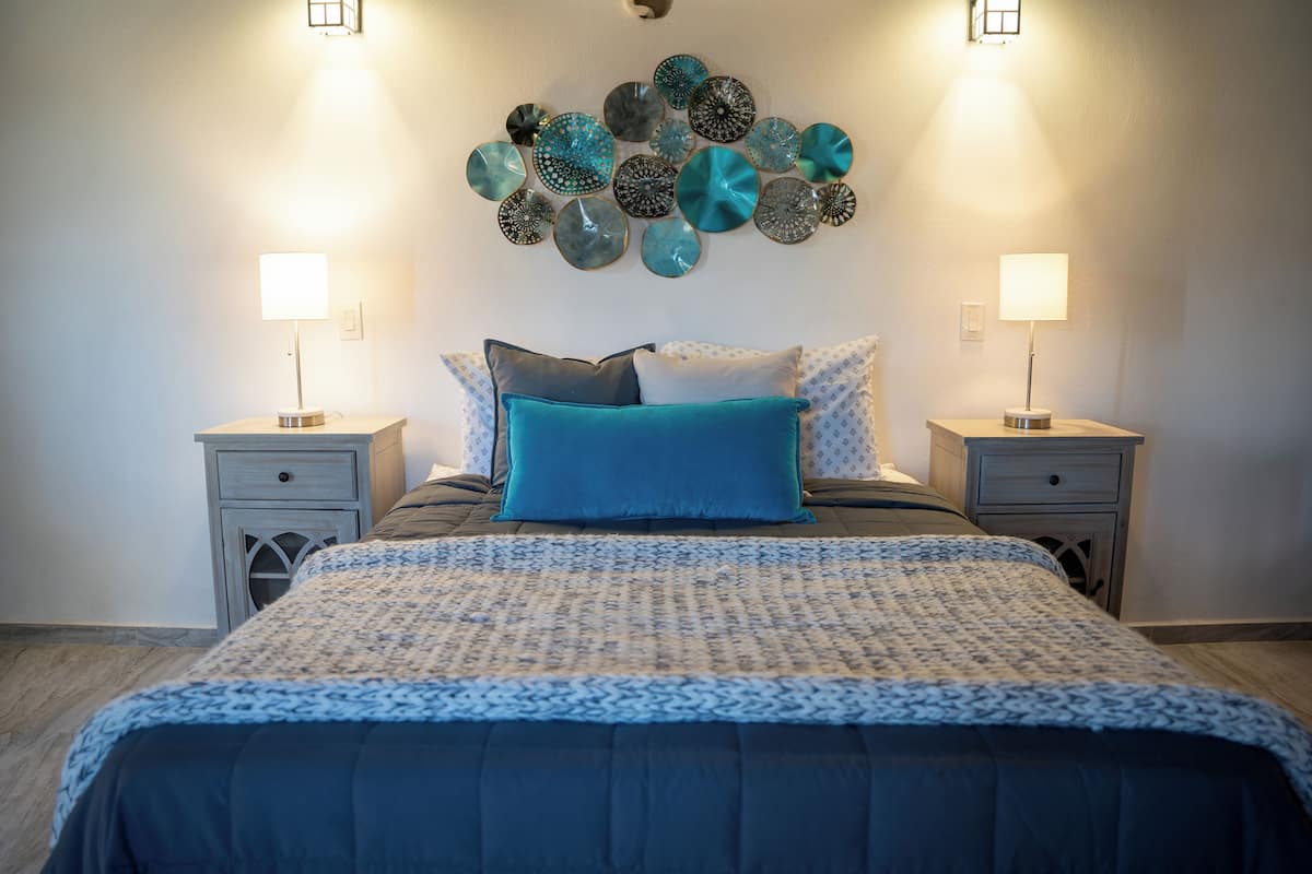 A bedroom with a bed, two bedside tables, and wall decor.