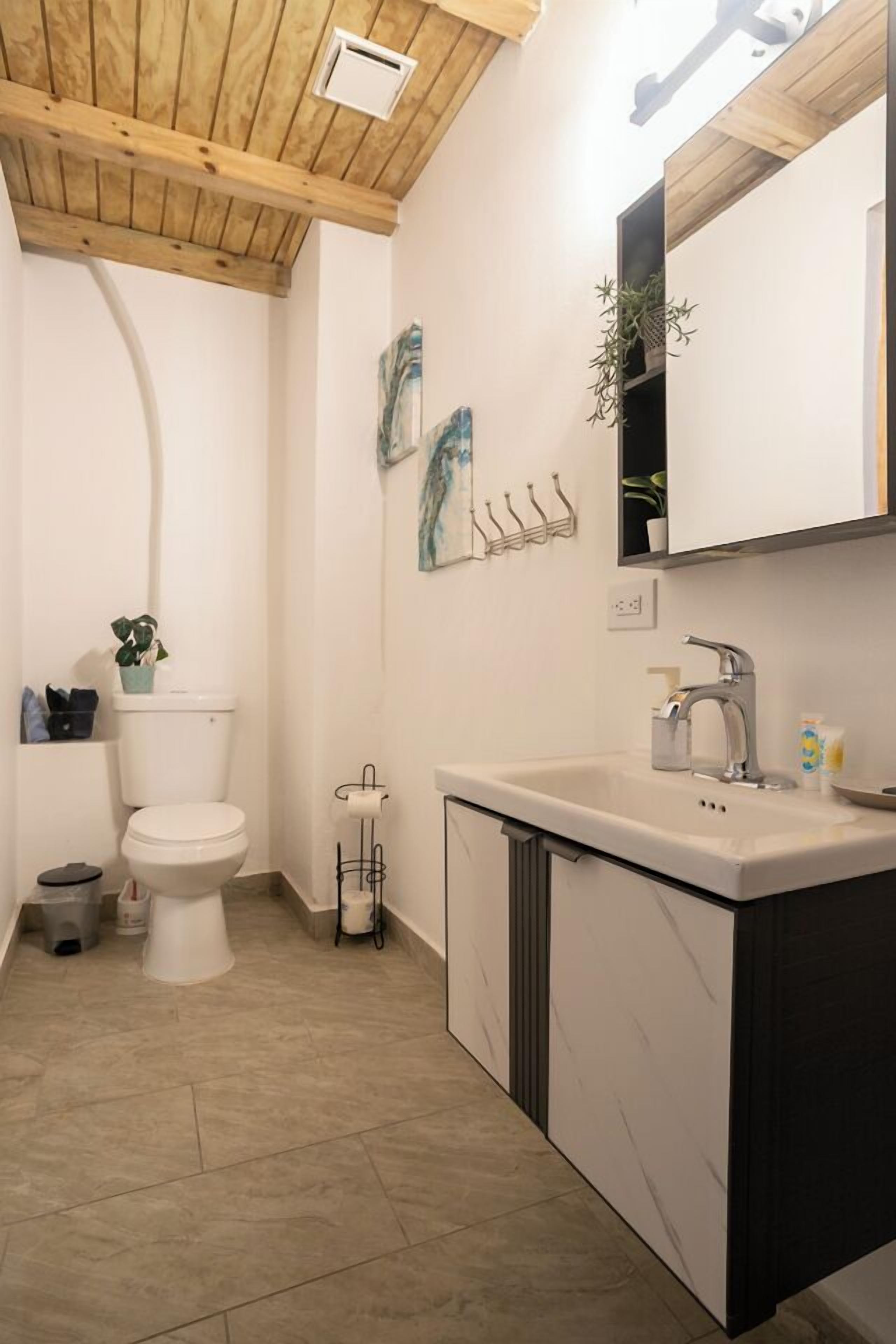 A modern bathroom with a toilet, sink, and mirror.