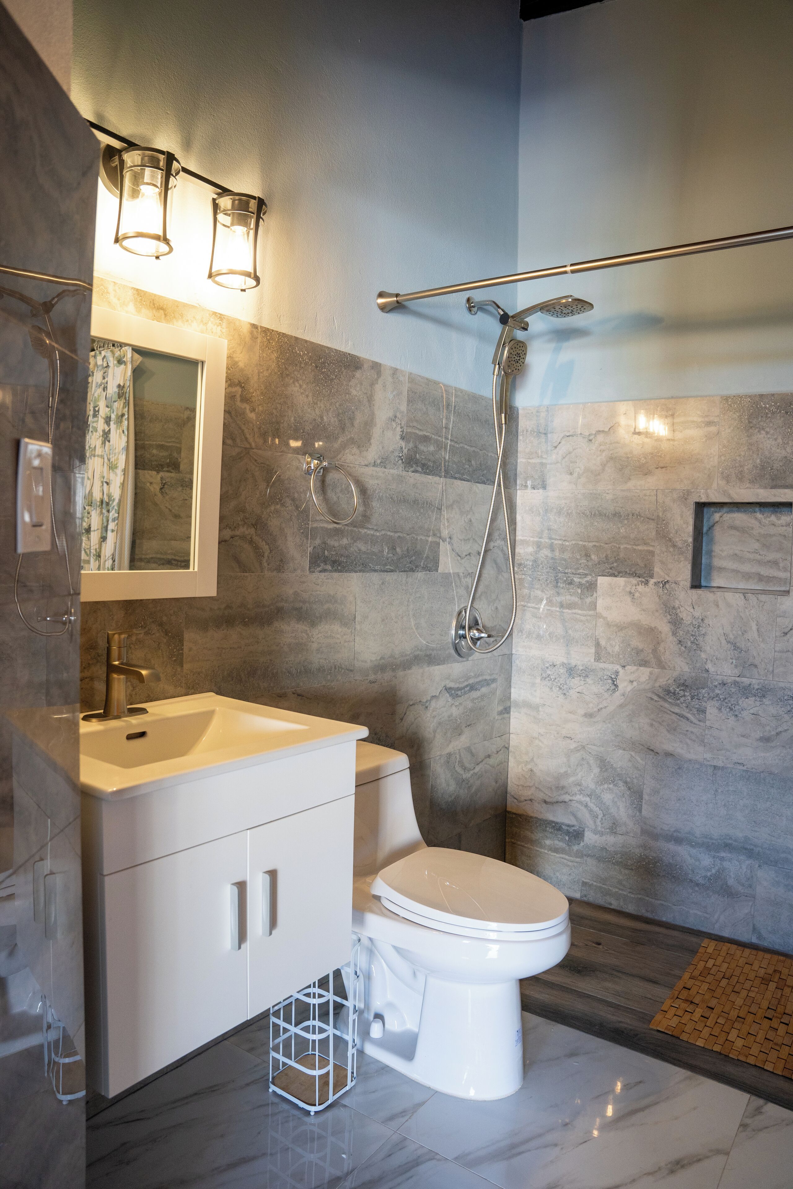 A modern bathroom with a white sink, toilet, and shower.