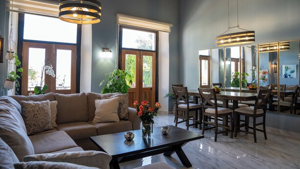 A spacious living room with a large sectional sofa, a dining table with chairs, and a chandelier. - Hugo's Rental (San Juan)