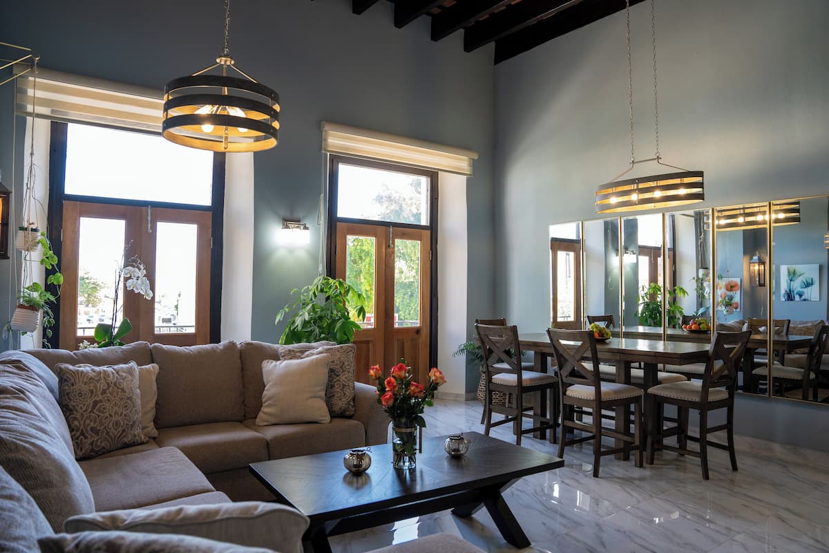 A spacious living room with a large sectional sofa, a dining table with chairs, and a chandelier.