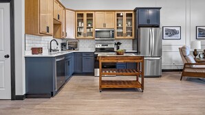 Una cocina moderna con armarios de madera, electrodomésticos de acero inoxidable y una mesa de madera.