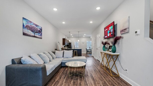 A modern living room with a sectional sofa, a coffee table, and a dining area in the background. - Luxury keyless free WiFi exit 11 (Clarksville)