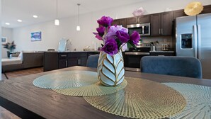 A modern kitchen with dark cabinets, stainless steel appliances, and a vase with purple flowers on a wooden table. - Luxury keyless free WiFi exit 11 (Clarksville)