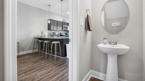 A modern kitchen with bar stools, a sink, and a mirror. - Luxury keyless free WiFi exit 11 (Clarksville)