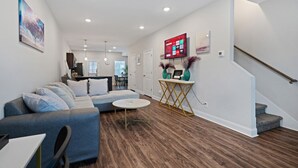 A modern living room with a sectional sofa, a round coffee table, and a staircase leading to another level. - Luxury keyless free WiFi exit 11 (Clarksville)