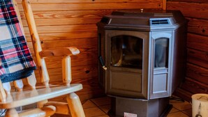 A cozy room with a wooden rocking chair, a wood-burning stove, and a caution sign on the floor.