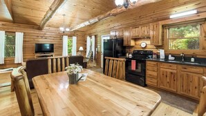 Ein Holzhäuschen-Interieur mit Essbereich, Küche und Fernseher.