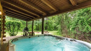 Ein Whirlpool unter einer Holzpergola mit Blick auf ein bewaldetes Gebiet.