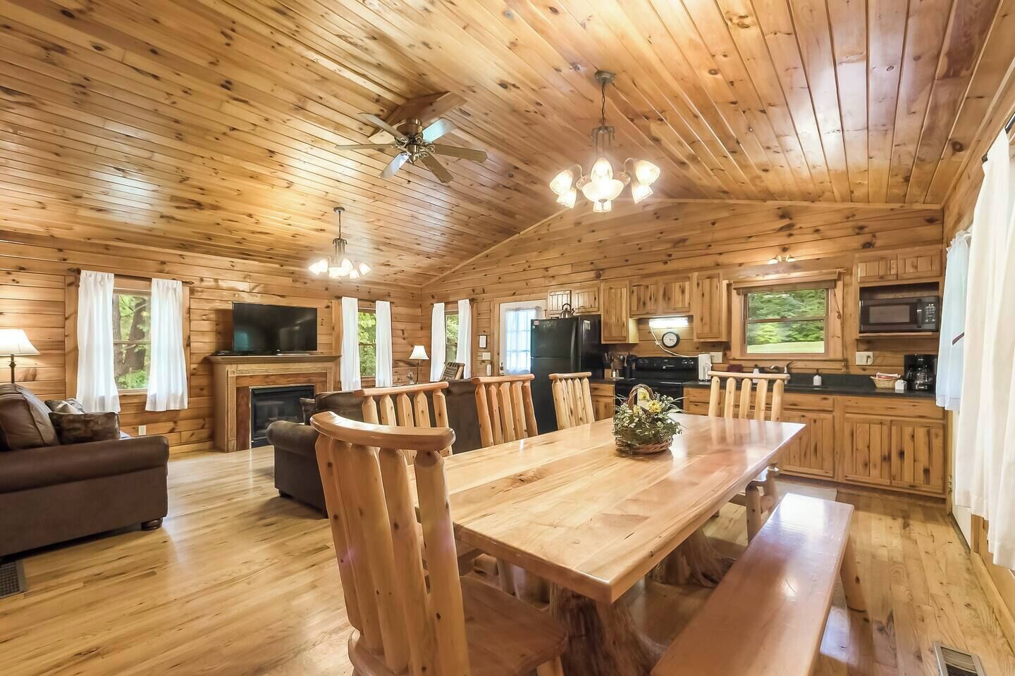 Interior de una cabaña de madera con comedor, cocina y sala de estar.