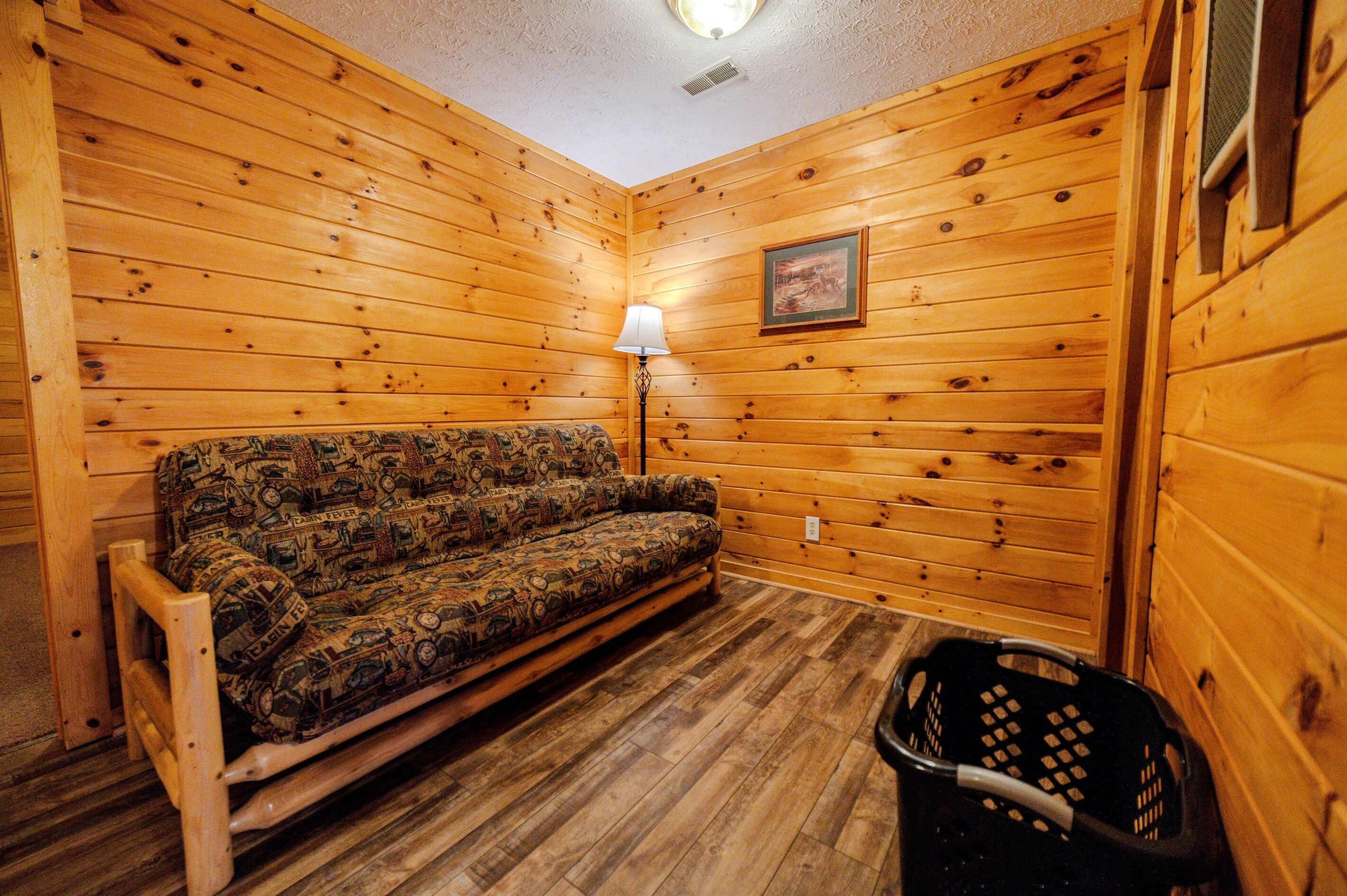 A wooden-paneled room with a sofa and a lamp.