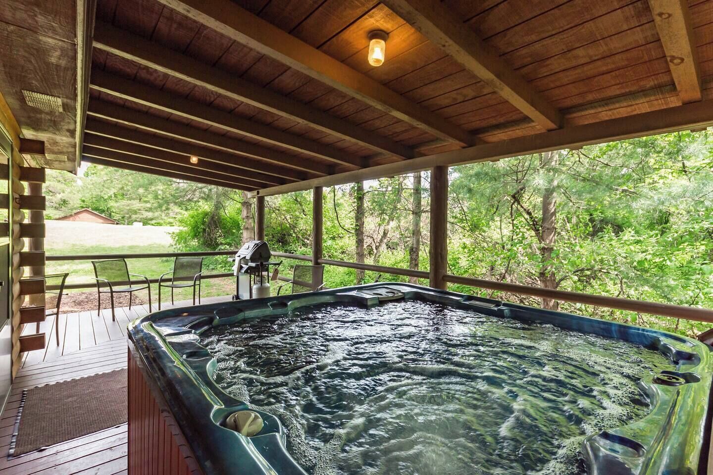 A hot tub under a wooden deck with a view of a wooded area.