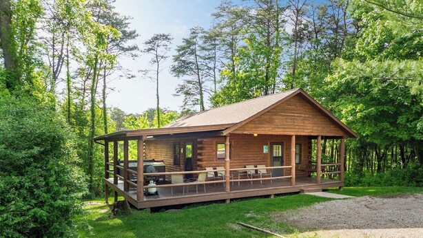 A wooden cabin with a porch, outdoor seating, and a grill area. - Family & Friends Getaway |Near Old Man's Cave (Logan)