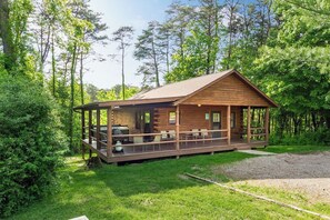 A wooden cabin with a porch, outdoor seating, and a grill area. - Family & Friends Getaway |Near Old Man's Cave (Logan)