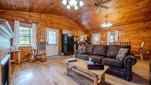 A wooden cabin interior with a living room, kitchen, and a fireplace. - Family & Friends Getaway |Near Old Man's Cave (Logan)