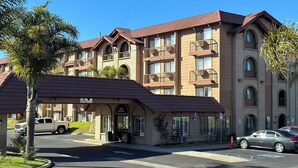 A multi-story hotel with a red-tiled roof, multiple balconies, and a clear sky.