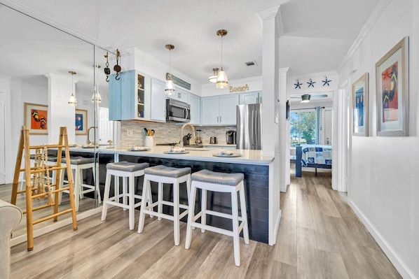 Una cocina moderna con una isla central, taburetes de bar e iluminación colgante.