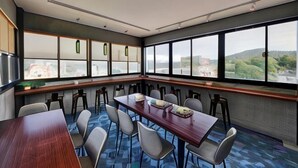 Une salle de conférence dotée d’une longue table, de nombreuses chaises et de grandes fenêtres donnant sur le paysage urbain.